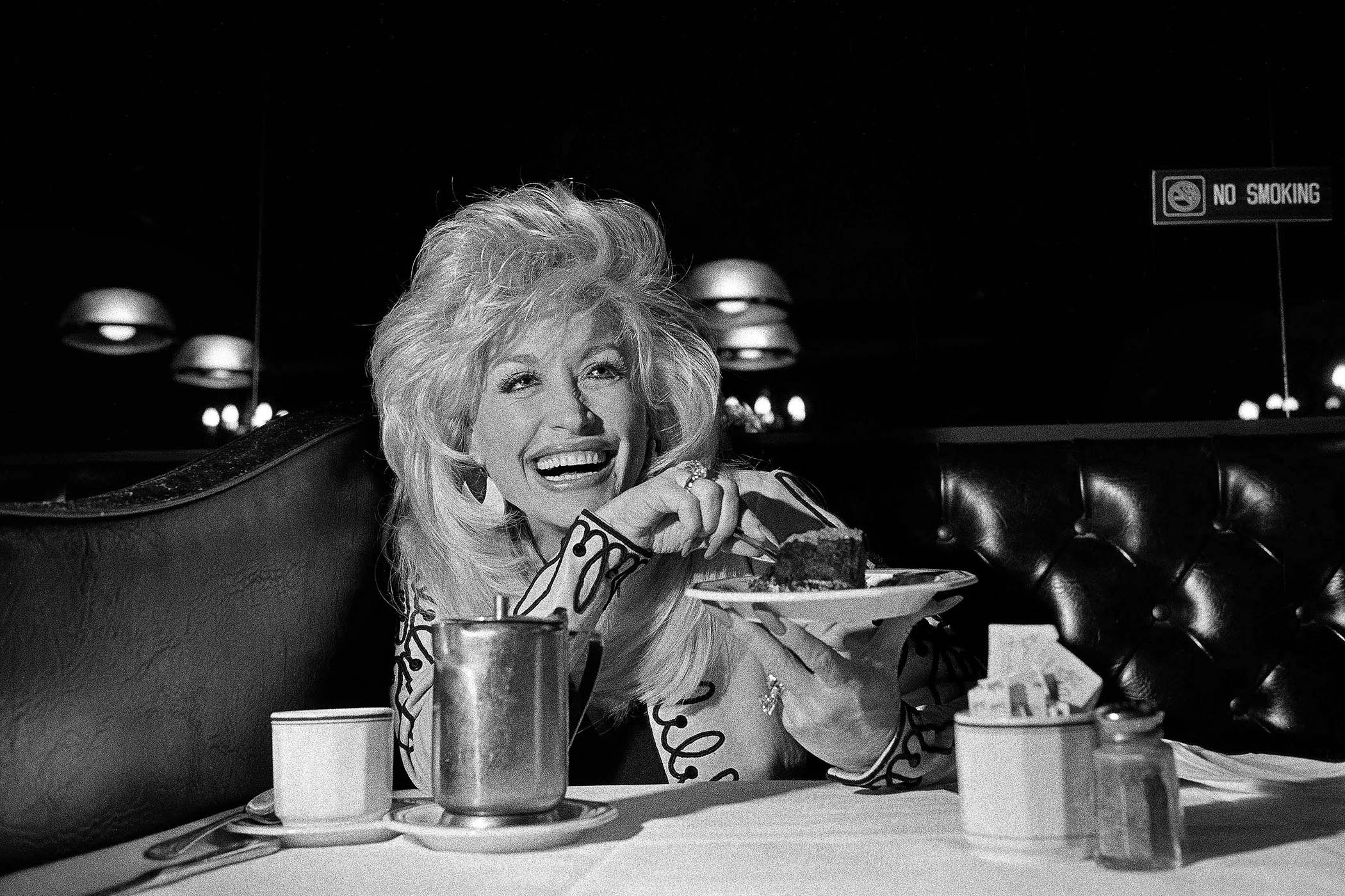 Dolly Parton at a diner table with cake, from Erica Wagner’s Observer remembrance.